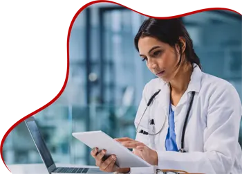 A doctor wearing a white coat and stethoscope uses a tablet while sitting at a desk with a laptop. The background shows a modern medical office with large windows. Red wavy design element frames the left side of the image.