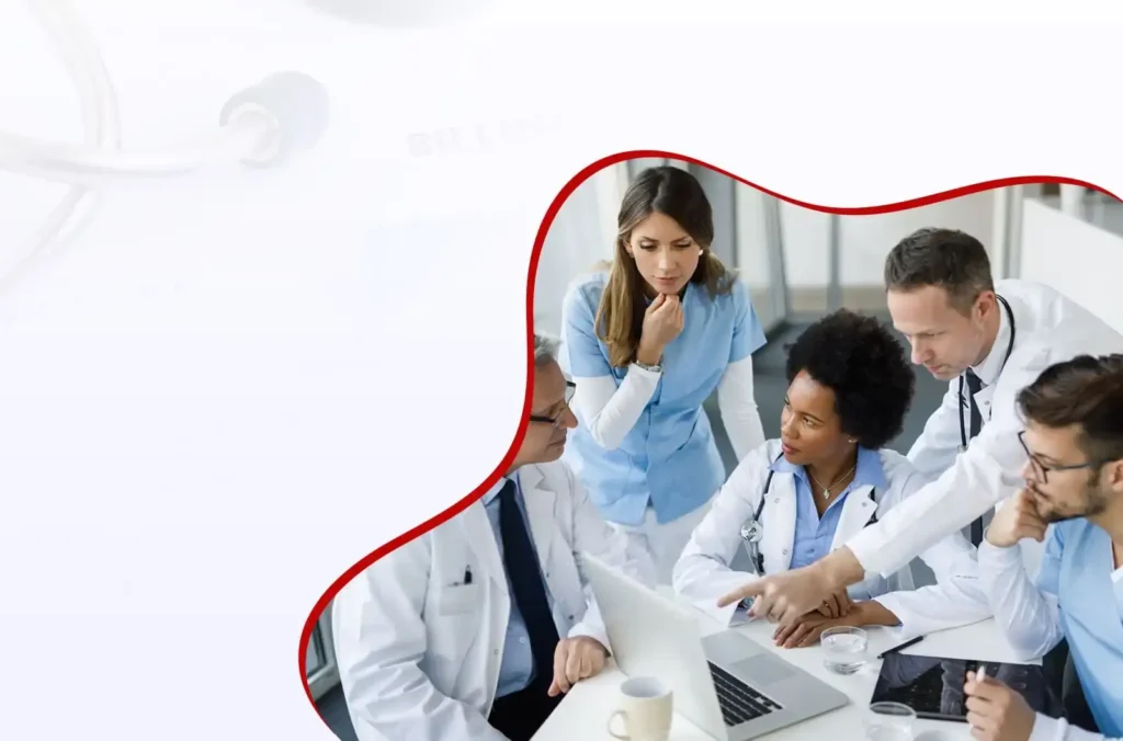 Four medical professionals, wearing white coats and scrubs, gather around a laptop discussing something, with coffee mugs and documents on the table in front of them.